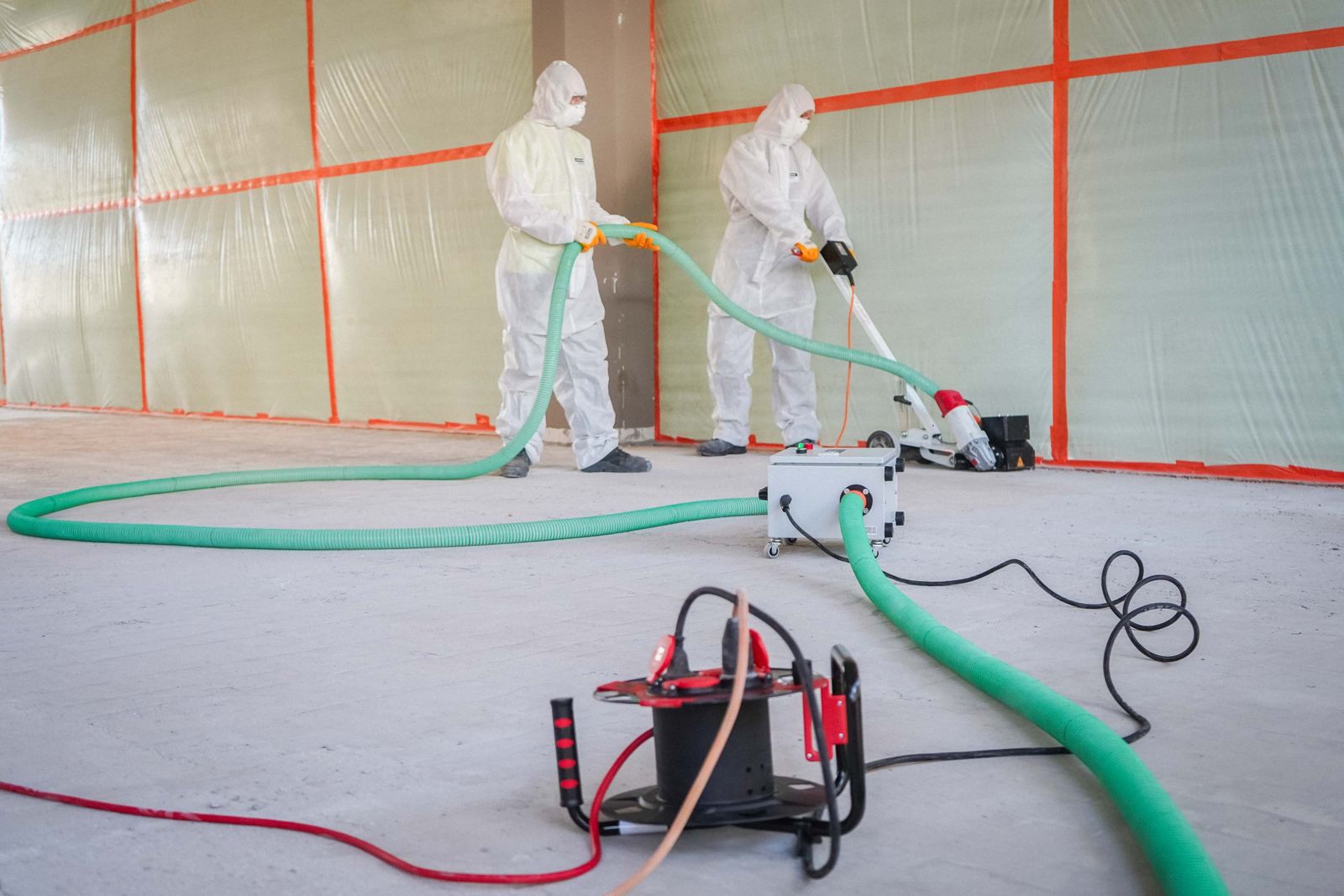 Foliengeschotteter Schwarzbereich mit zwei HSM-Mitarbeitern bei der Bodensanierung und professioneller Absaugtechnik