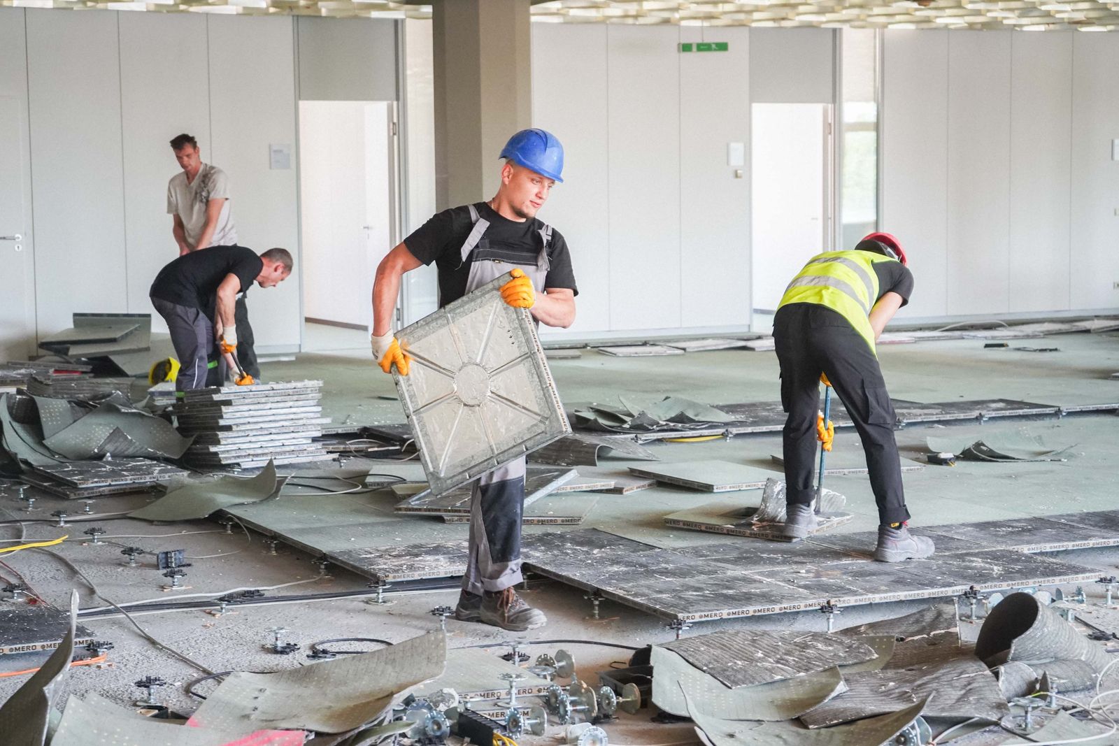 Zwei HSM-Mitarbeiter demontieren Bodenplatten beim selektiven Innenrückbau