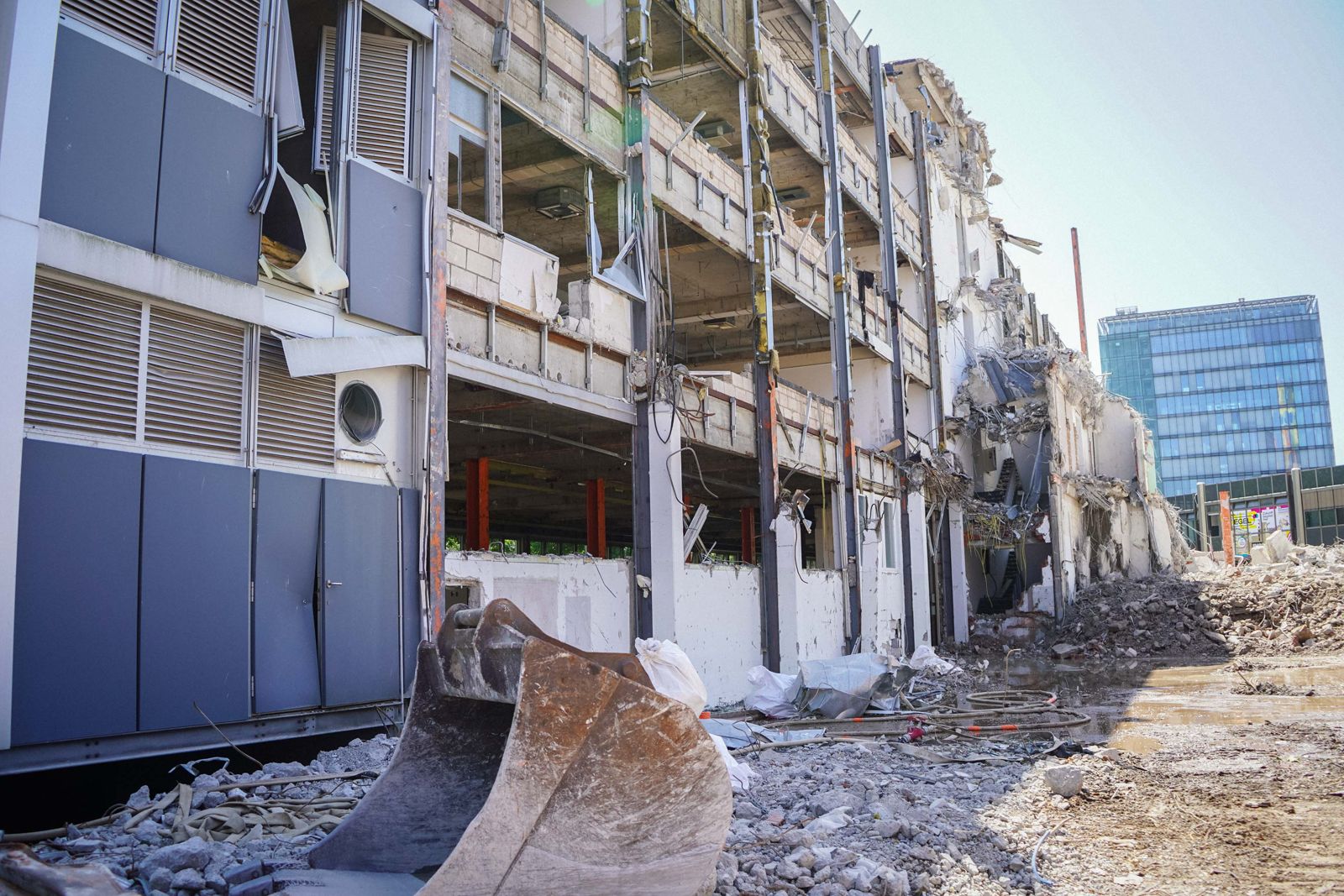 Bagger beim Rückbau eines mehrgeschossigen Gebäudes mit Fassadendemontage