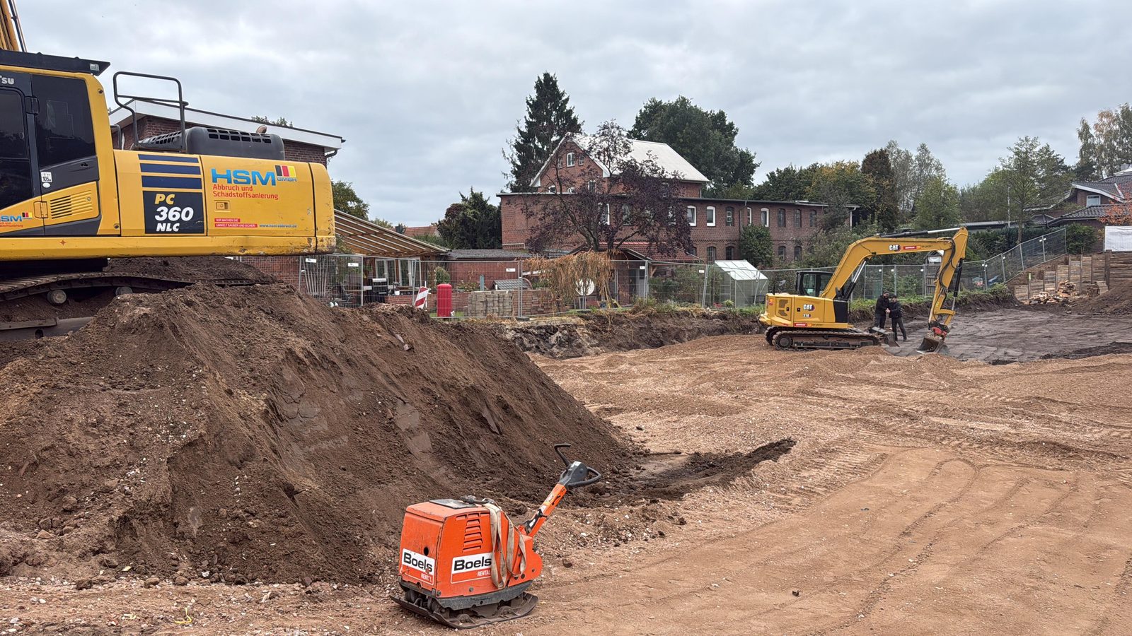 Gelber HSM-Bagger mit Firmenlogo auf einer Erdbau-Baustelle mit Bodenmodellierung